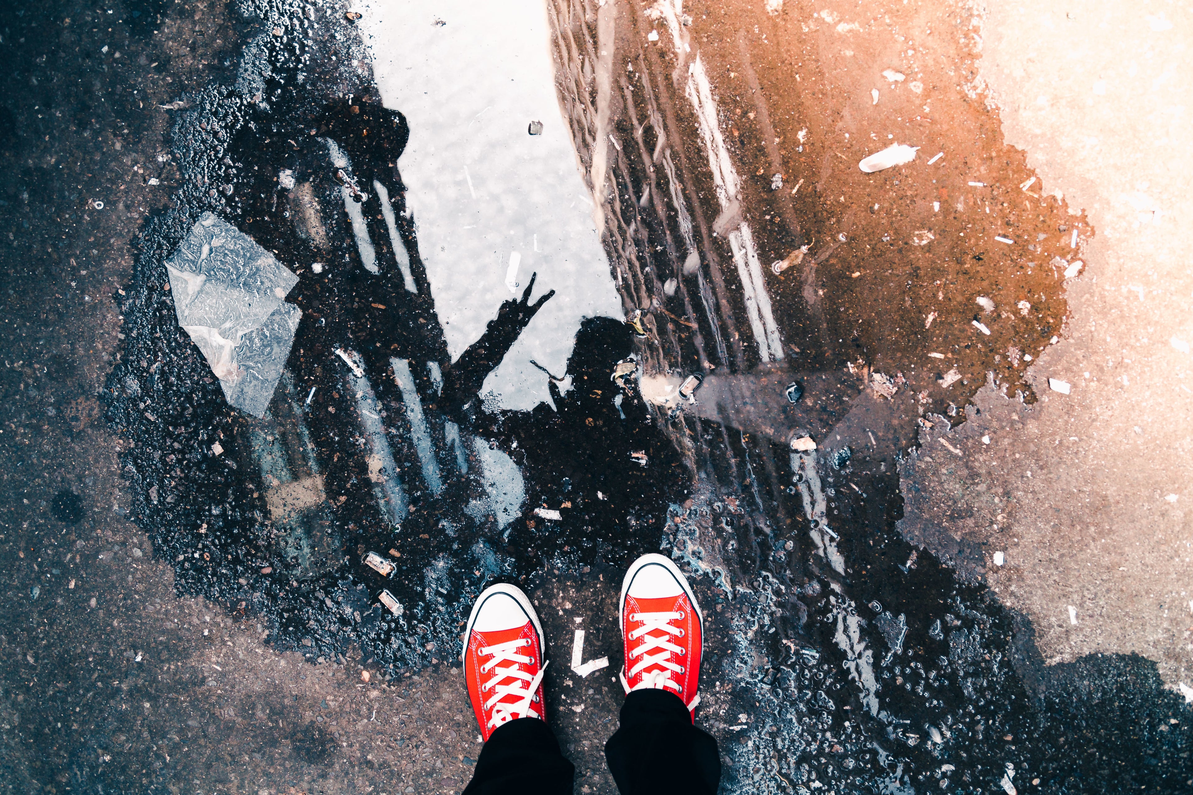Youth standing in red sneakers with a puddle reflection showing a peace sign for GFTB Networks upcoming kids cultural streetwear collection.